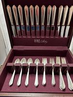 Full set of 12 dinner knives displayed in upper tier of burgundy case
