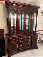 Front view of the Sumter Cabinet Co. wood cabinet showing glass display doors and drawers.