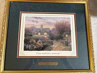 Full view of first framed print titled 'Come inside for a warm-up' showing gold-tone frame and embossed mat