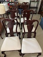 Frontal view of wooden chairs with cream seats arranged in rows
