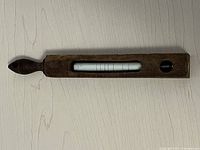Full-length view of the wooden thermometer case showing the carved handle and cutout window displaying the thermometer tube.