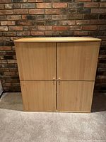 Front view of closed 4-door IKEA shelving unit showing light wood finish and round wood door knobs.