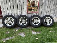 Full view of four Audi alloy rims with winter tires showing overall condition against a rustic wood backdrop.