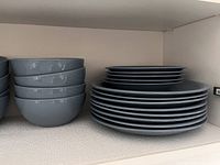 Blue dinner plates, side plates, and cereal bowls stacked on shelf.