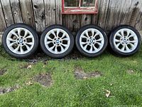 Four wheel and tire assemblies lined up against a wooden background