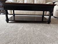 Closer side/front view showing table leg and lattice design elements, as well as shelf below