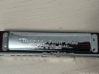 Close-up of the harmonica's polished metal surface showing engraved Trutone Pitch Pipe marking with M.Hohner branding and model number NP23.