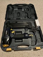 Open case showing Mastercraft air powered nailer with accessories and white box inside the molded compartments.