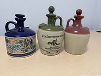 Front view of three ceramic steins on table showing labels and stopper lids.