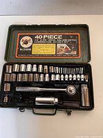 Top-down view of open metal case showing the layout of sockets, ratchet, and accessories in the set.