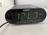 Front view of Sony alarm clock radio powered on displaying 12:10 with FM and AM radio frequency markings.