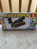 Boxed Sportstuff Descender inflatable sled with sled seen on box art showing rider lying down in black gear, highlighting size, features, and single rider capacity.