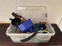 Plastic container with various automotive-related items including funnel, rope, motor oil bottle, traction device box, and manual tools.