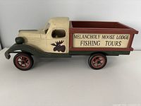 Side view of wooden vintage truck showing painted signage and moose graphic on the door.