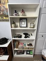 Full front view of the white IKEA bookcase holding various decorative items and books on shelves to show shelf count and size.