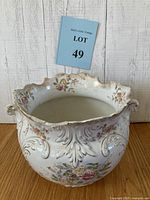 Front angle view of the antique Victorian planter showing floral patterns, embossed designs, scalloped rim with gold trim, and handles.