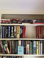 Bookshelves filled with various books covering multiple genres including thrillers, military fiction, and golf instruction