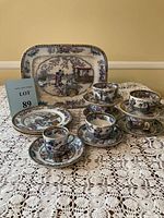 Full view of the large serving platter with 5 demitasse cups and 7 saucers displayed on a lace cloth, showcasing the intricate colorful Chinese pattern with gold rims.