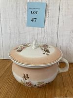 Antique ceramic chamber pot with lid, hand painted floral decoration and gilt rim, shown from front angle
