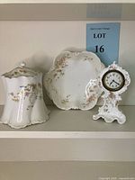 Three-piece lot showing serving bowl, sugar bowl, and decorative clock with floral gold accents on a white porcelain base.