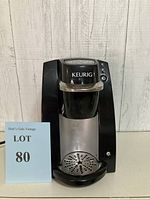 Front view of Keurig B30 Mini single-serve coffee maker showing overall unit with drip tray and brand name.
