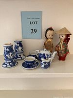 Group shot showing the two Asian 1950s spool dolls, the miniature blue and white porcelain tea set, and the two candlestick holders on shelf.