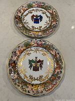 Top view showing two antique Capodimonte dinner plates with armorial crests at center and raised cherub figures around borders.