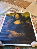 Full view of the unframed painted canvas of the Mona Lisa laid out on the floor.