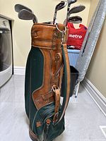 Full view of green and brown Burton leather golf bag with clubs inside