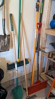 Photo of various garden tools hanging on a wall, including shovels, rake, broom