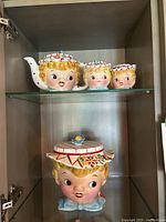 Front view of teapot, salt & pepper shakers on top shelf, cookie jar on bottom shelf