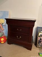 Front view of the cherry wood night table with two drawers and metal handles, showing overall condition and design.