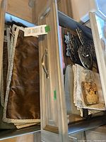 Two open wooden drawers filled with placemats, napkins, coasters, and metal hot plates