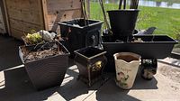Wide view of all assorted planters including black resin lion head planter, sheep hooks, dragonflies, and other plastic planters.