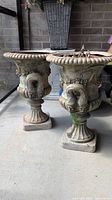 Two matched footed urn style planters standing on concrete surface, showing overall size and appearance