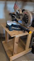 Full view of miter saw mounted on wooden table frame with casters