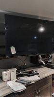 Mounted Samsung TV, two remotes, user manual, TP-Link extender boxes on shelf
