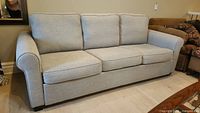 Front view of three-cushion roll-arm sofa bed in light grey fabric