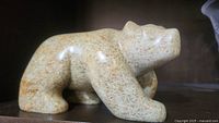 Front side view of light beige speckled stone bear sculpture showing the head and body details