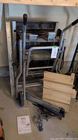 Folded table saw and cart with loose accessories on garage floor