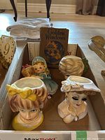 Overview of box containing three head vases, Lefton wall pocket and book