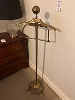 Full view of the brass tone wardrobe butler showing the hanger, base, and overall height.