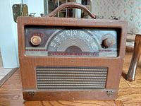 Front view of antique General Electric Beamascope police radio showing dial, knobs, speaker grille, and leather covering.