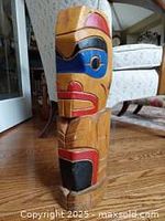 Side view of the totem showing carved and painted profile details with blue, red, and black paint.
