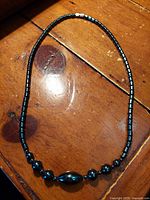 Hematite stone necklace laid out flat on a wooden surface showing bead arrangement and overall length.