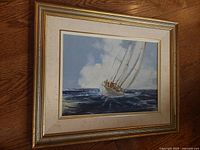 Framed oil on board painting of a sailing crew on turbulent waters with cloudy sky, in giltwood frame with linen mat.