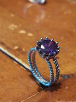 Close-up side angle of the sterling silver ring showing twisted rope design band and purple faceted gemstone in claw setting