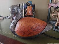 Side view of the bronze and stained glass duck lamp unlit, showing textured bronze metal body and amber stained glass wing.