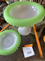Shows compote dish on pedestal and matching plate with green Vaseline glass rim placed on glass table