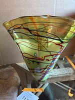 Photo showing full front view of green translucent conical Murano glass vase with colorful swirls and irregular flared rim.